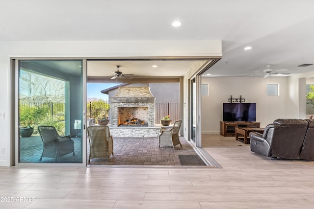 living room with ceiling fan, a fireplace, and light wood-type flooring