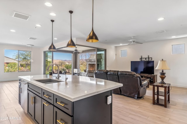 kitchen featuring sink, hanging light fixtures, a center island with sink, light hardwood / wood-style flooring, and ceiling fan