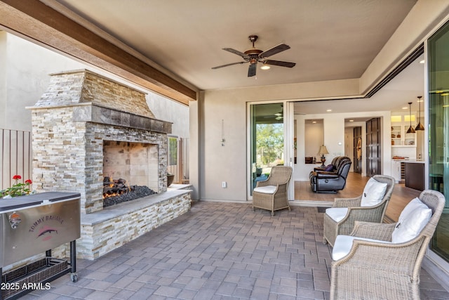 view of patio with ceiling fan and an outdoor stone fireplace