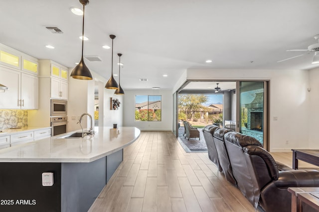 kitchen with stainless steel appliances, sink, hanging light fixtures, and white cabinets