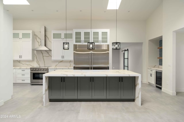 kitchen with white cabinetry, wall chimney range hood, wine cooler, a spacious island, and appliances with stainless steel finishes