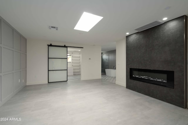 unfurnished living room featuring a fireplace and a barn door