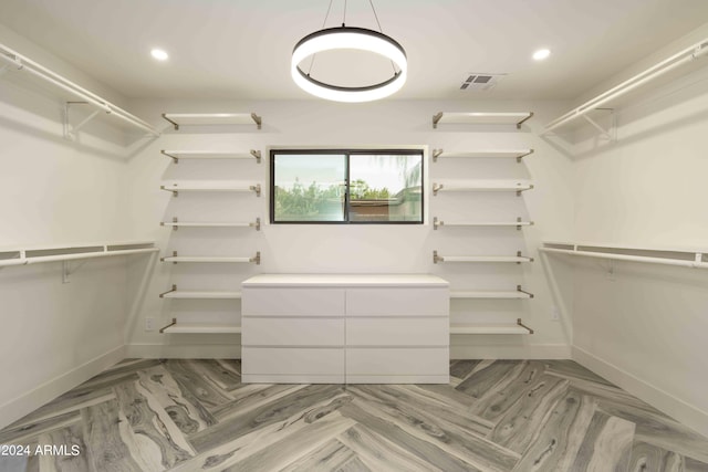 walk in closet with parquet flooring