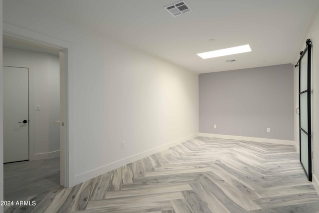 spare room with a barn door and light parquet floors