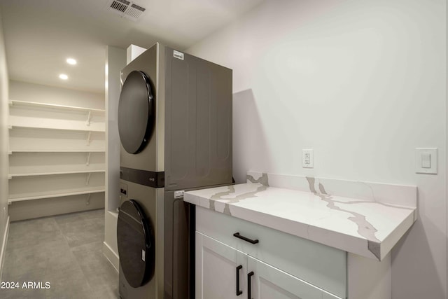 clothes washing area featuring cabinets and stacked washer / dryer