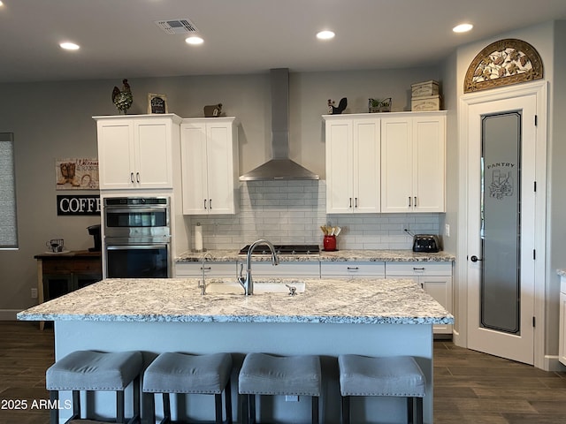 4114 Copperhead Dr, Wickenburg, AZ 85390 - kitchen featuring wall chimney exhaust hood, stainless steel appliances, a sink, a kitchen breakfast bar, and dark wood-style flooring