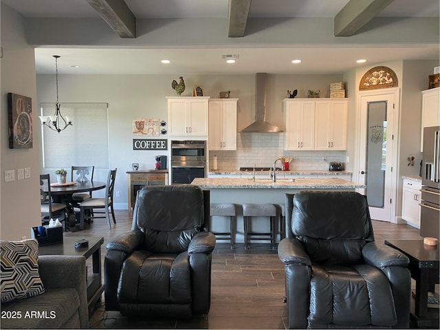 4114 Copperhead Dr, Wickenburg, AZ 85390 - kitchen with wall chimney exhaust hood, stainless steel double oven, beamed ceiling, dark wood-type flooring, and open floor plan