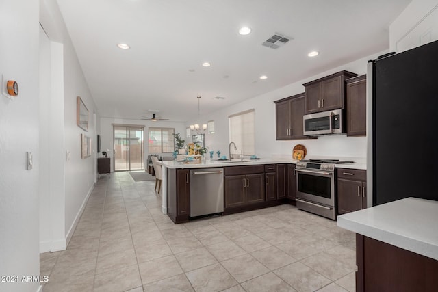 kitchen with sink, hanging light fixtures, kitchen peninsula, ceiling fan with notable chandelier, and appliances with stainless steel finishes