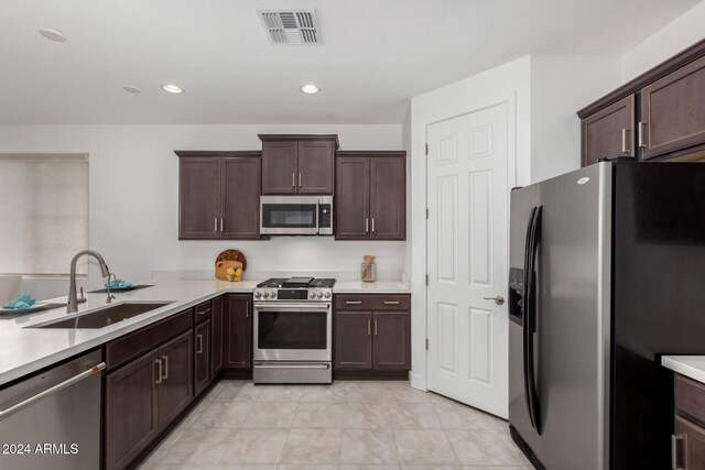 kitchen with kitchen peninsula, sink, dark brown cabinets, and appliances with stainless steel finishes