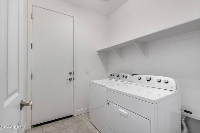 clothes washing area with washer and clothes dryer and light tile patterned floors