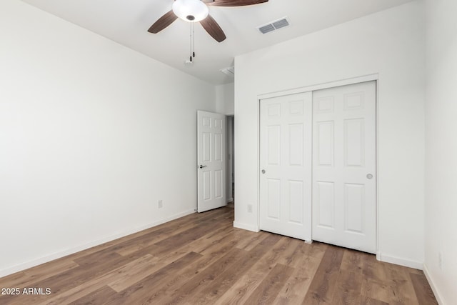 unfurnished bedroom featuring hardwood / wood-style floors, ceiling fan, and a closet