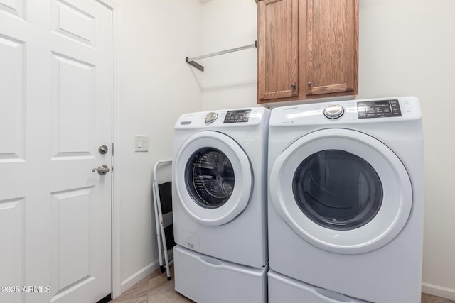 washroom featuring washer and dryer, cabinets, and light tile patterned floors