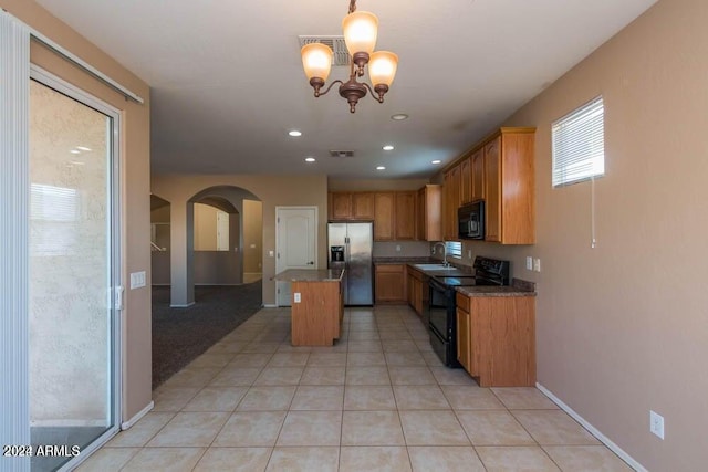 kitchen with sink, a center island, a notable chandelier, pendant lighting, and black appliances