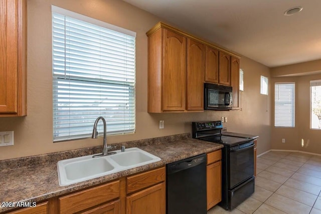 kitchen featuring light tile patterned floors, a wealth of natural light, sink, and black appliances