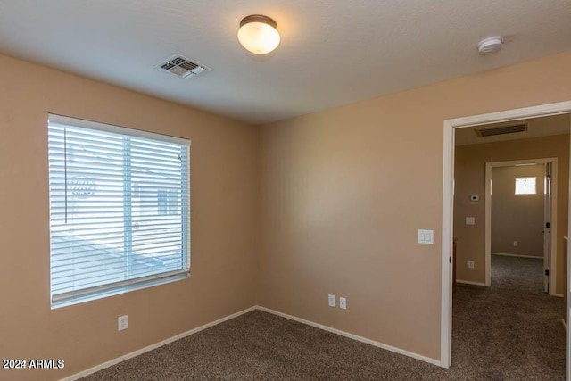 spare room featuring dark colored carpet