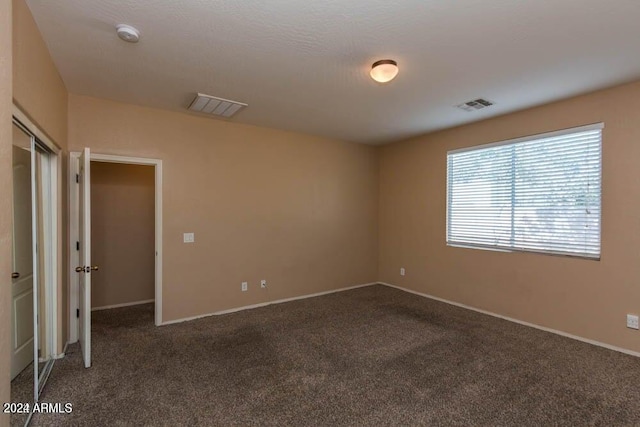 spare room featuring dark carpet