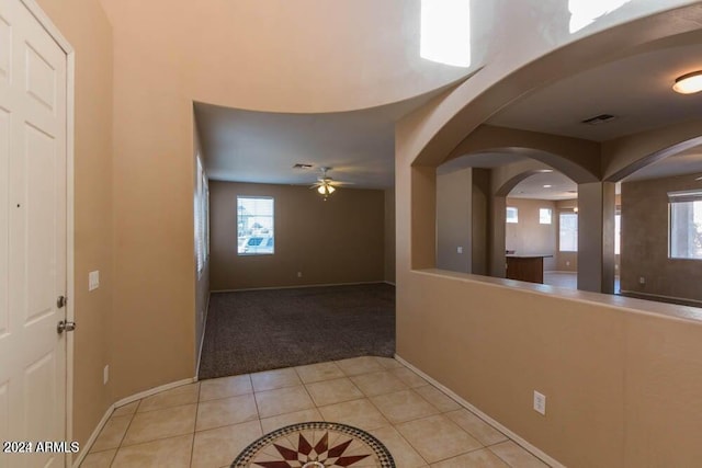 foyer entrance featuring ceiling fan, a wealth of natural light, and light tile patterned floors