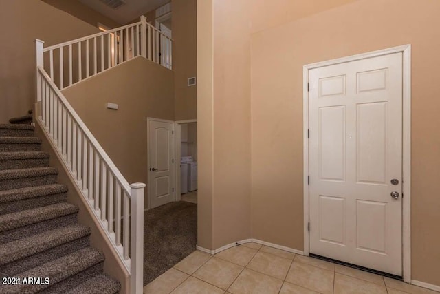 entrance foyer with washer / clothes dryer, a high ceiling, and light tile patterned flooring