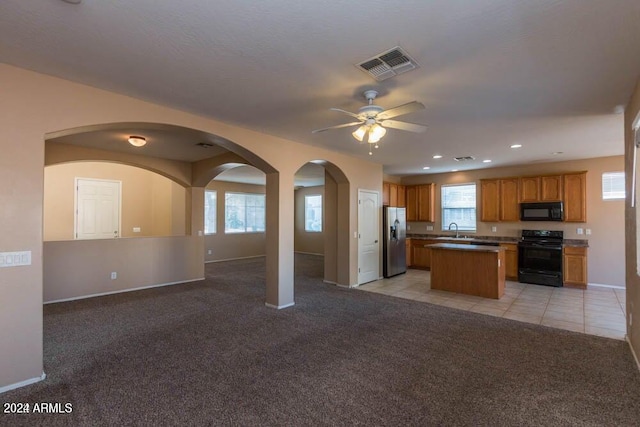 kitchen with range with electric cooktop, a center island, a wealth of natural light, stainless steel fridge with ice dispenser, and light colored carpet