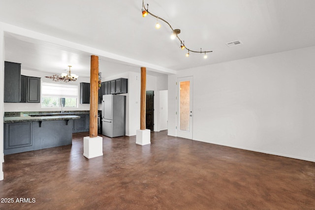 6310 E Dove Valley Rd, Cave Creek, AZ 85331 - kitchen featuring freestanding refrigerator, open floor plan, a chandelier, a kitchen bar, and concrete flooring