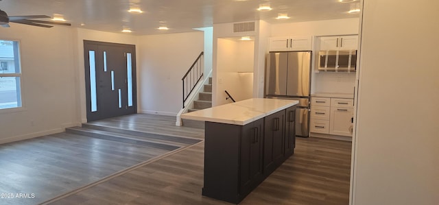 interior space featuring dark wood-style flooring, a kitchen island, freestanding refrigerator, and white cabinetry