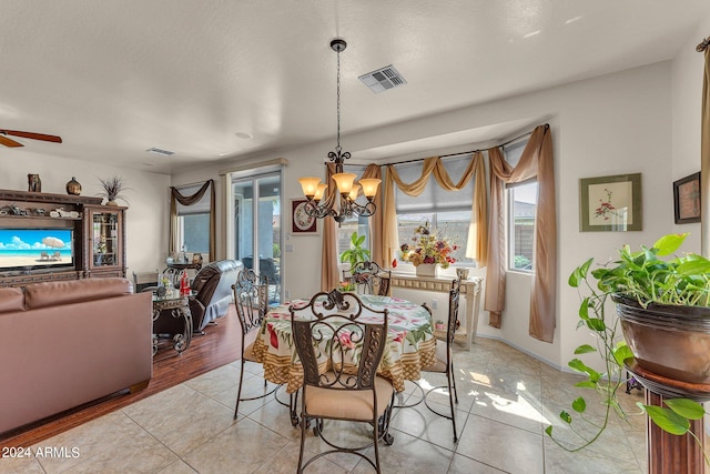 dining room with ceiling fan with notable chandelier and light hardwood / wood-style flooring