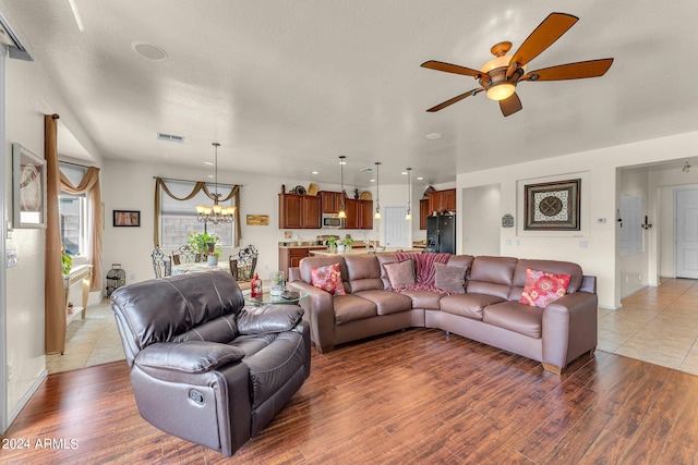 living room with ceiling fan with notable chandelier and dark hardwood / wood-style flooring