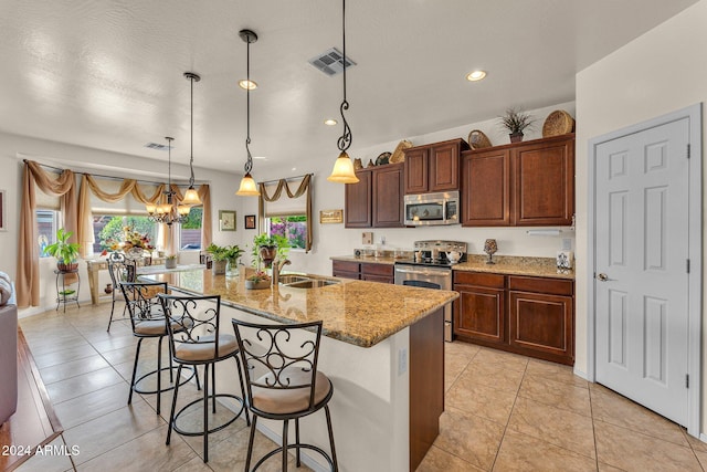 kitchen with stainless steel appliances, a center island with sink, a breakfast bar area, and decorative light fixtures