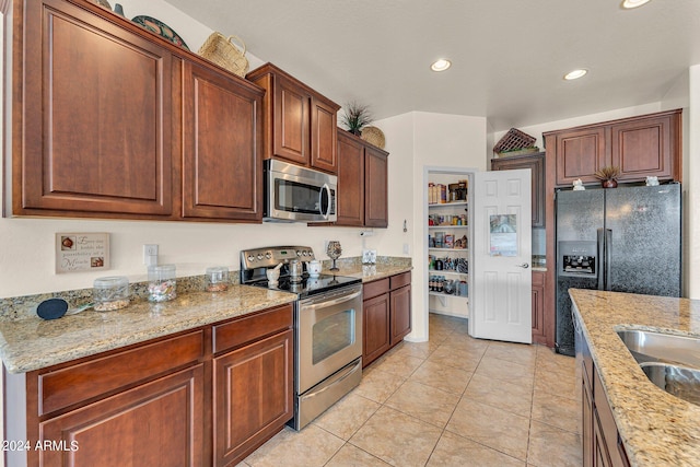 kitchen featuring stainless steel appliances, light tile patterned flooring, light stone counters, and sink