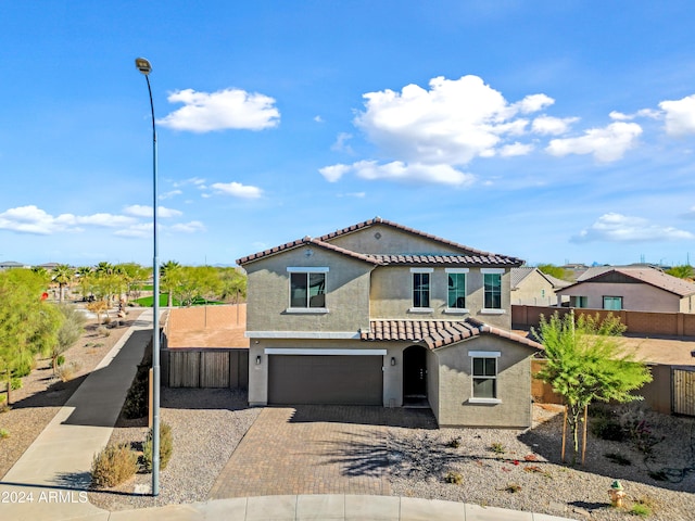 mediterranean / spanish-style house featuring a tiled roof, fence, decorative driveway, and stucco siding