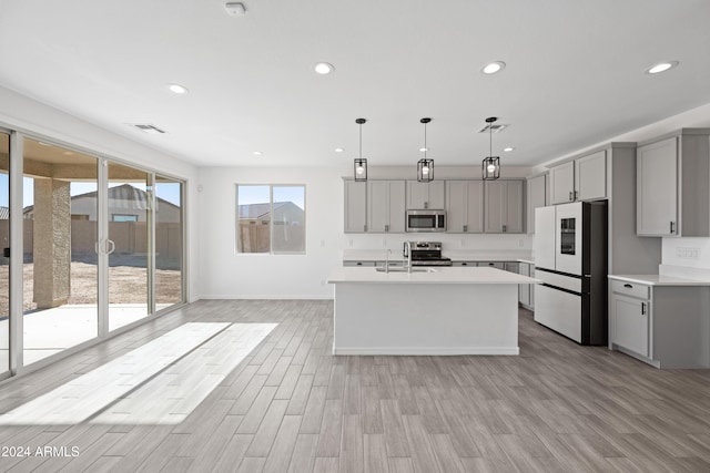 kitchen with recessed lighting, light countertops, appliances with stainless steel finishes, gray cabinets, and light wood finished floors