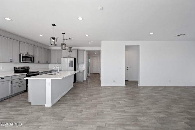 kitchen with appliances with stainless steel finishes, open floor plan, a sink, and gray cabinetry