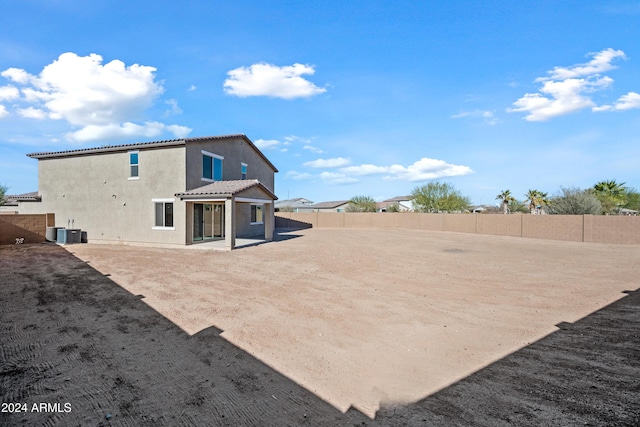 back of property with a tiled roof, central air condition unit, a fenced backyard, and stucco siding