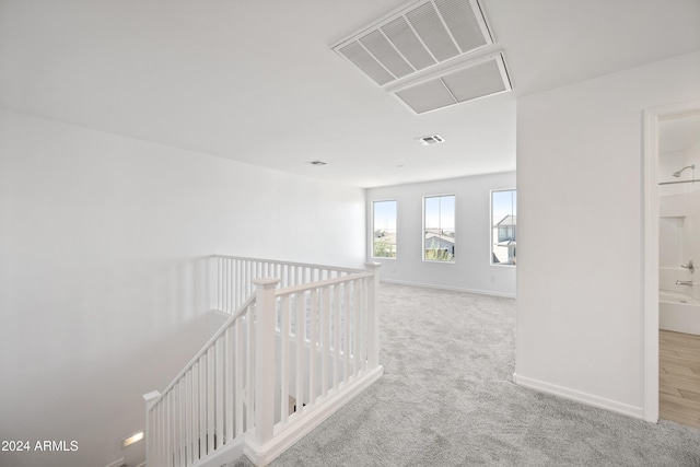 corridor featuring carpet floors, baseboards, visible vents, and an upstairs landing