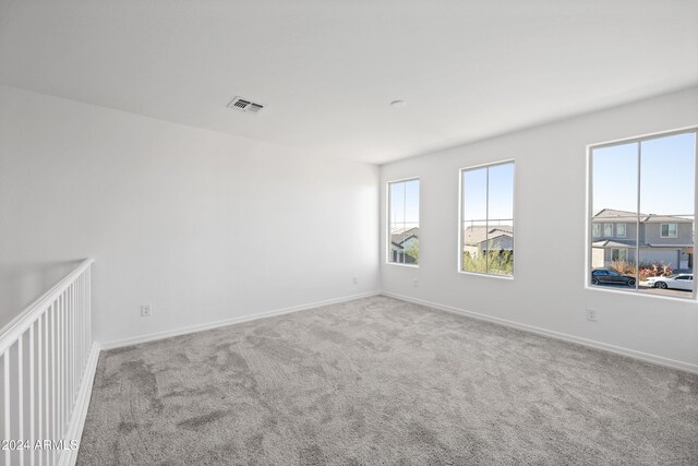 carpeted empty room featuring visible vents and baseboards