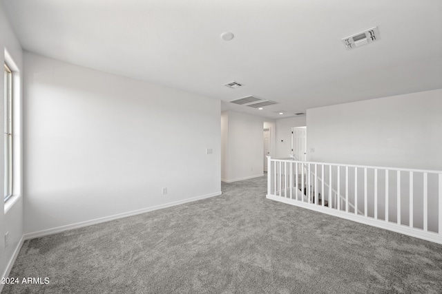 unfurnished room with carpet floors, visible vents, and baseboards