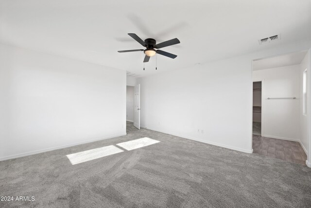 carpeted empty room with ceiling fan, visible vents, and baseboards