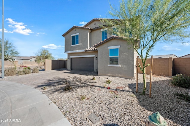 mediterranean / spanish home featuring an attached garage, fence, a tiled roof, driveway, and stucco siding