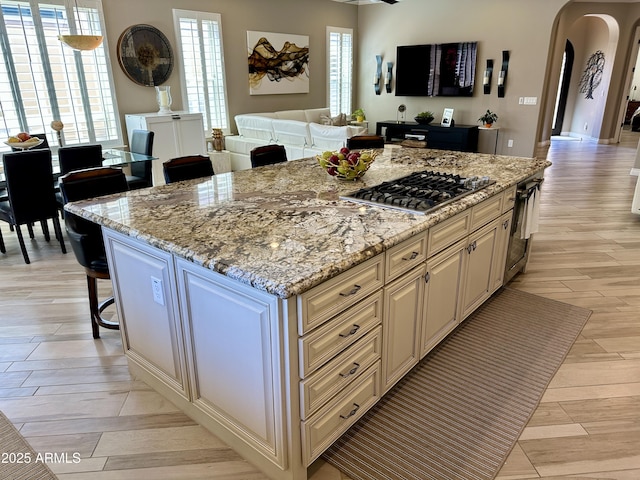 562 E Vesper Trl, Queen Creek, AZ 85140 - kitchen featuring stainless steel gas cooktop, arched walkways, open floor plan, cream cabinetry, and light wood-style floors