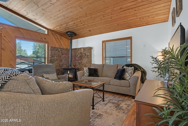living room featuring wood finished floors, wooden walls, wood ceiling, a wood stove, and lofted ceiling
