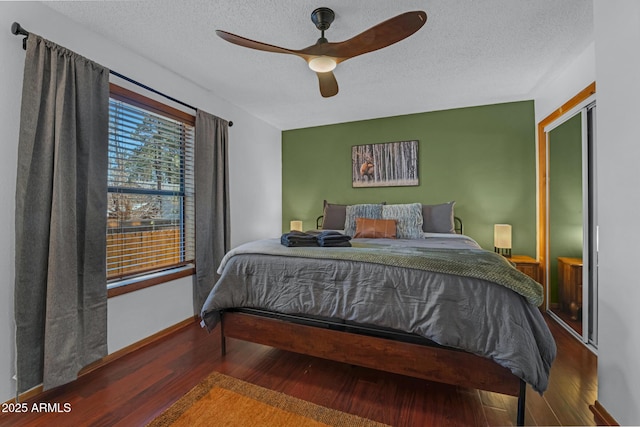 bedroom featuring wood finished floors, a textured ceiling, and baseboards