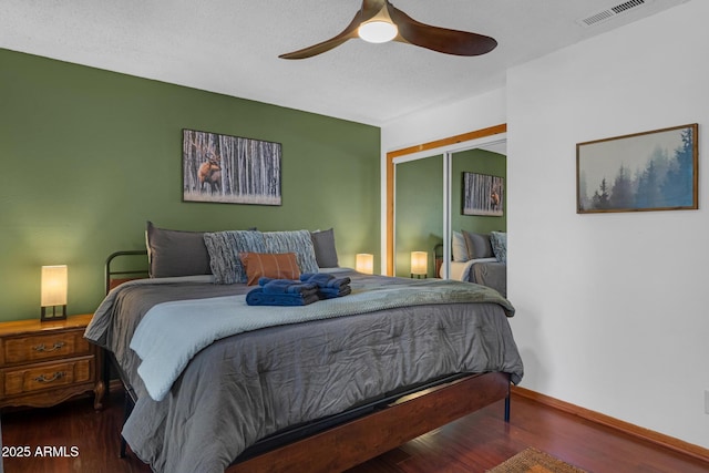 bedroom featuring visible vents, baseboards, a ceiling fan, wood finished floors, and a closet