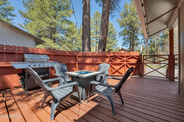 deck featuring a fire pit, area for grilling, and fence