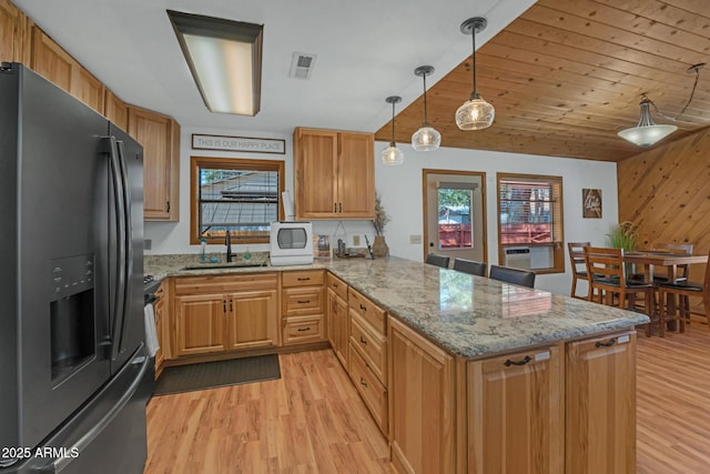 kitchen featuring a sink, black fridge with ice dispenser, light wood finished floors, a peninsula, and visible vents
