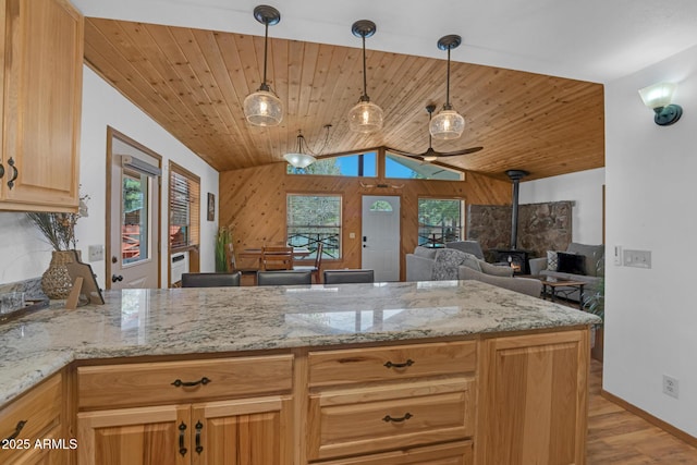 kitchen with light stone countertops, light wood-style flooring, wooden ceiling, and a wood stove
