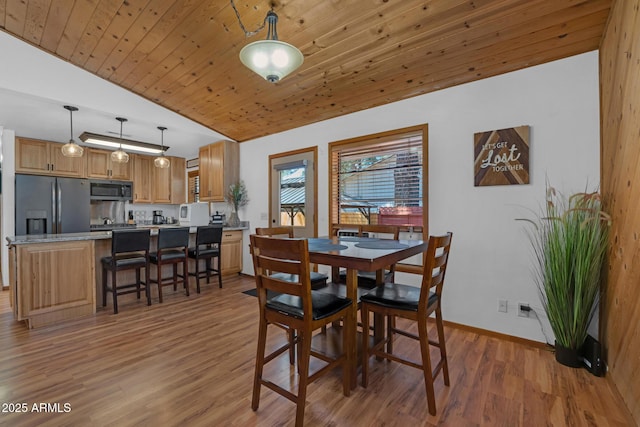 dining space featuring lofted ceiling, light wood finished floors, baseboards, and wooden ceiling