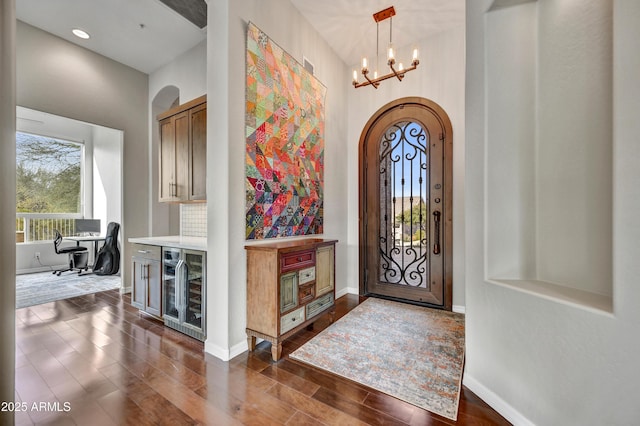 entryway with dark hardwood / wood-style flooring, an inviting chandelier, and beverage cooler