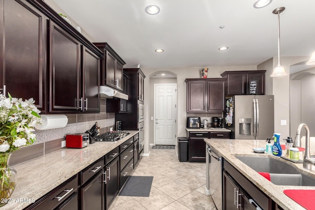 kitchen featuring pendant lighting, sink, decorative backsplash, light stone countertops, and appliances with stainless steel finishes