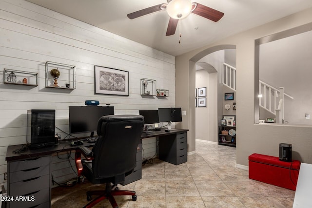 office space featuring ceiling fan and wood walls