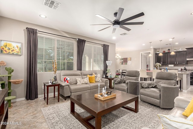 tiled living room featuring ceiling fan with notable chandelier and plenty of natural light